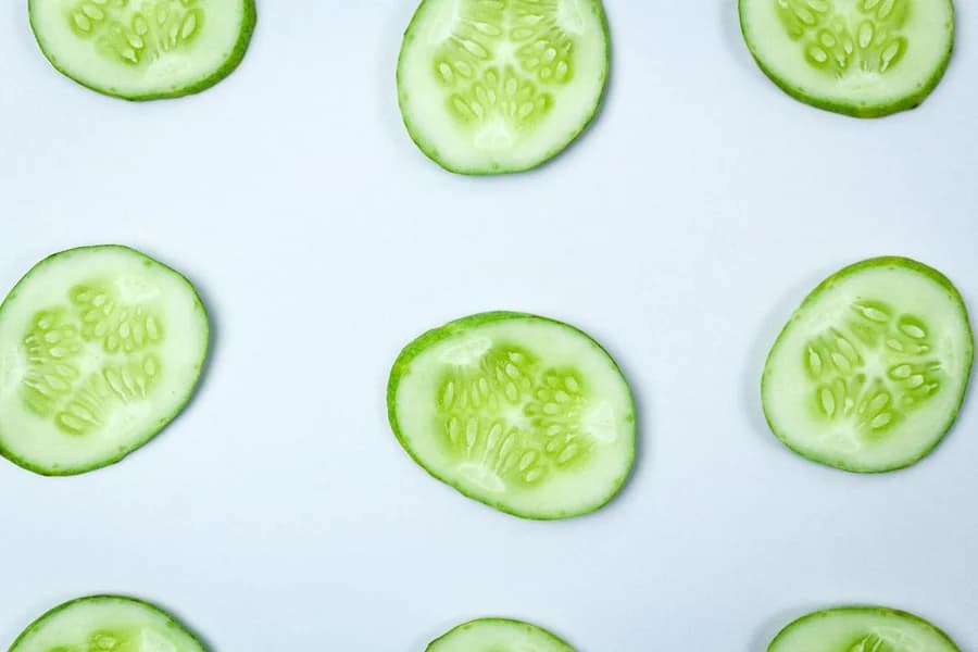Fresh cucumber rounds photographed on a pale surface.
